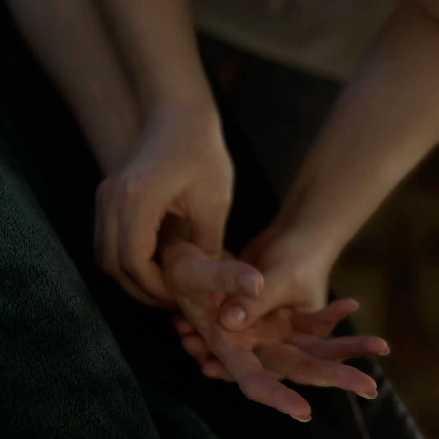 Mãos de um casal entrelaçadas em ambiente de penumbra